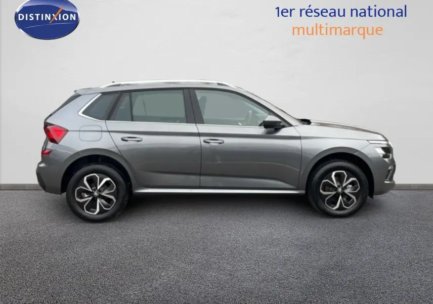 Profil côté droit d'un Skoda Kamiq 2025 gris graphite métallisé avec jantes bi-ton et toit équipé de barres de toit.