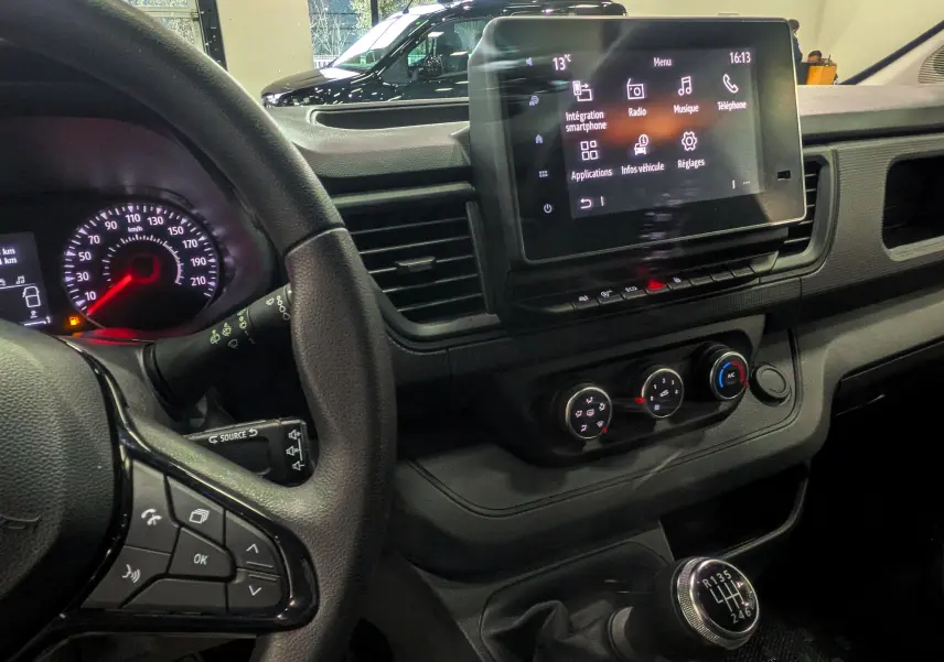 Vue intérieure côté conducteur du Renault Trafic Combi gris, montrant le volant, tableau de bord et écran tactile central.