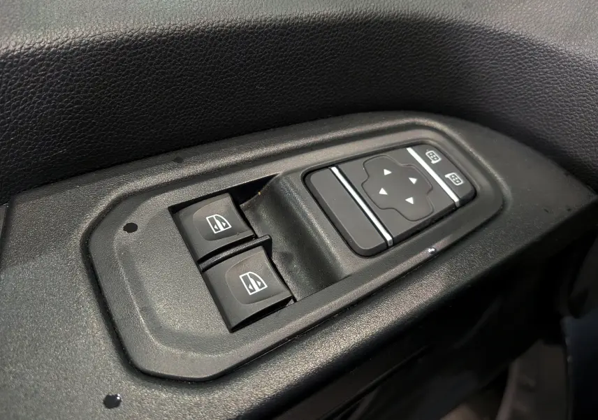 Commande électrique des vitres et réglage des rétroviseurs sur la porte côté conducteur du Renault Trafic Combi gris Comète 2023.