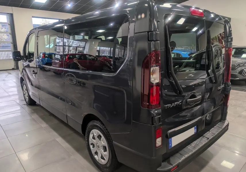 Vue 3/4 arrière droite du Renault Trafic Combi gris Comète, mettant en valeur ses grandes vitres latérales et portes arrière vitrées.