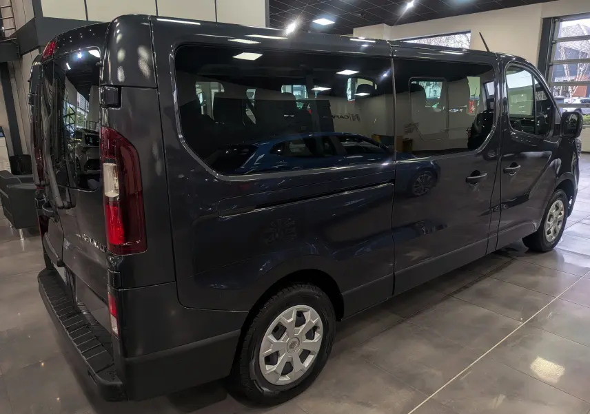 Vue 3/4 arrière droite du Renault Trafic Combi gris Comète 2023, mettant en valeur ses grandes vitres latérales et ses jantes.