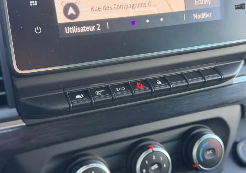 Gros plan sur la console centrale du Nissan Primastar Combi 2025, boutons de contrôle et écran tactile visibles.