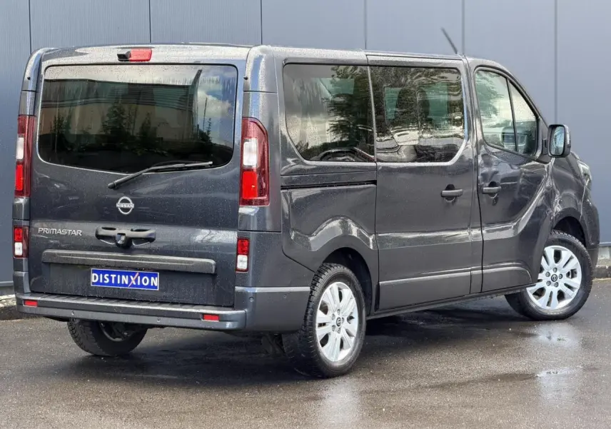 Vue 3/4 arrière droite du Nissan Primastar Combi gris comète avec hayon vitré et jantes alliage 17 pouces.