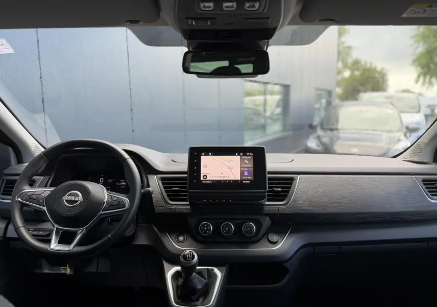 Vue intérieure frontale du tableau de bord gris du Nissan Primastar Combi avec écran tactile et volant multifonctions.