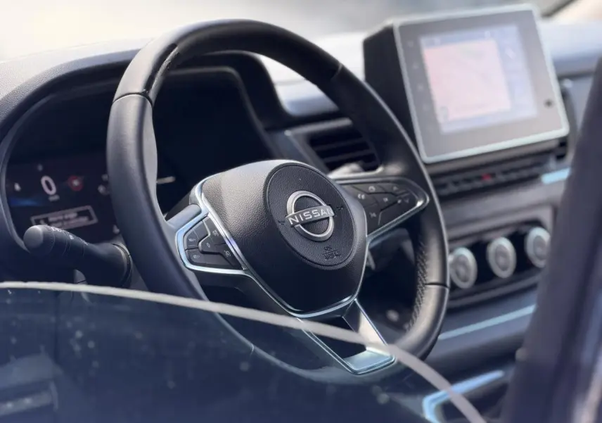 Vue rapprochée du volant noir et du tableau de bord avec écran tactile du Nissan Primastar Combi 2025.
