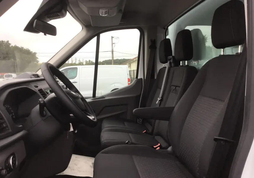 Intérieur du Ford Transit Chassis Cabine blanc, vue côté conducteur montrant les sièges noirs et le tableau de bord.