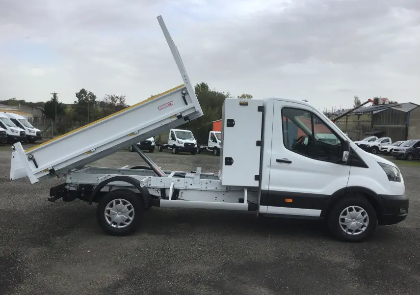 Vue latérale droite d'un Ford Transit blanc avec benne relevée et coffre acier sur châssis cabine.