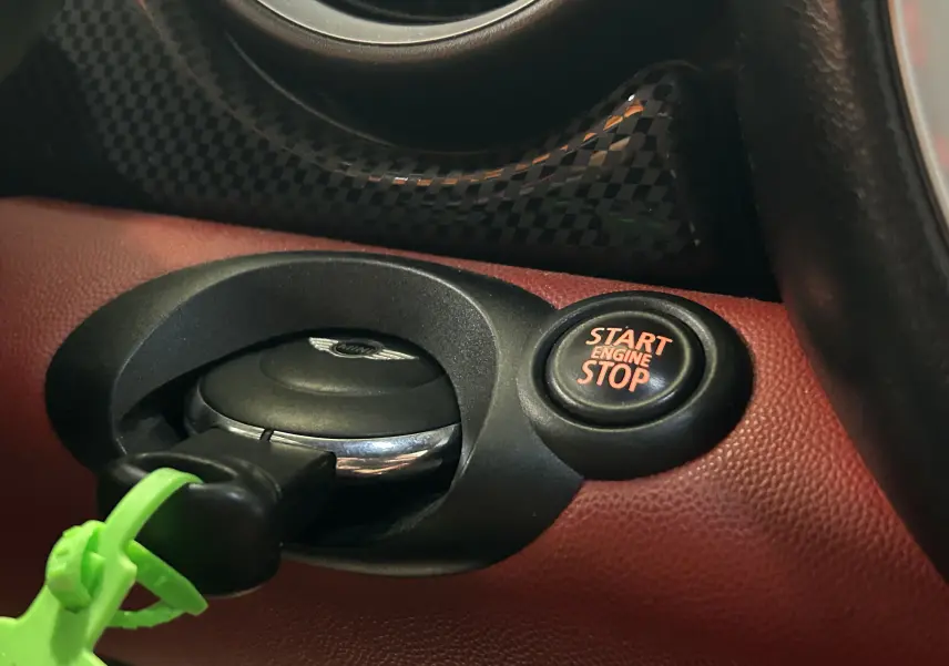 Gros plan sur les interrupteurs chromés du plafonnier intérieur d'une MINI Cabriolet rouge de 2012, éclairage bleu visible.