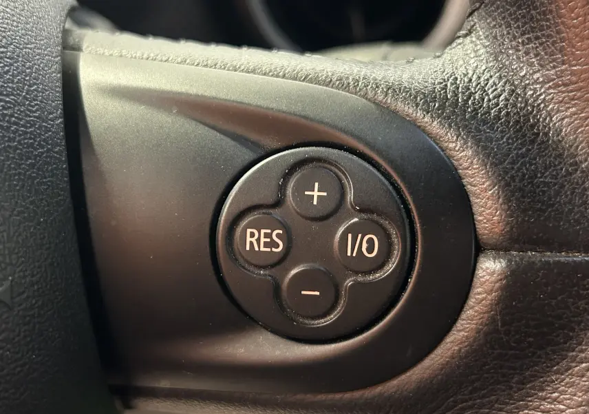 Gros plan sur les commandes de volume et téléphone au volant noir du MINI Cabriolet Cooper S rouge de 2012.