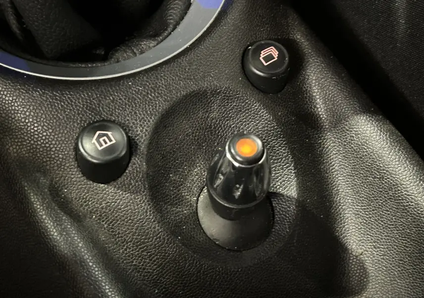 Gros plan sur les commandes de régulateur de vitesse sur le volant en cuir noir d'une MINI Cabriolet rouge 2012.