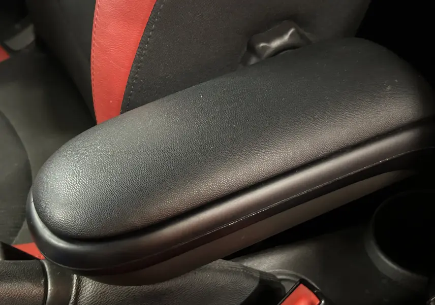 Vue de côté gauche en léger plongé d'une MINI Cabriolet Cooper S rouge avec capote noire partiellement ouverte et sièges bicolores rouges et noirs.