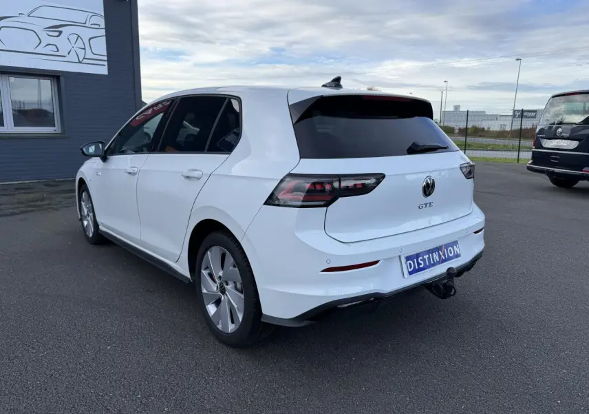 Volkswagen Golf 1.5 eHybrid blanc nacré vue 3/4 arrière droit avec attelage escamotable et vitres surteintées.