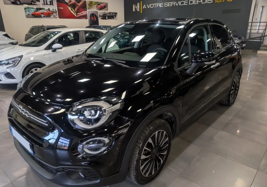 Vue 3/4 avant droite d'une FIAT 500X 2024 noir cinéma, avec jantes alliage et phares LED en showroom.