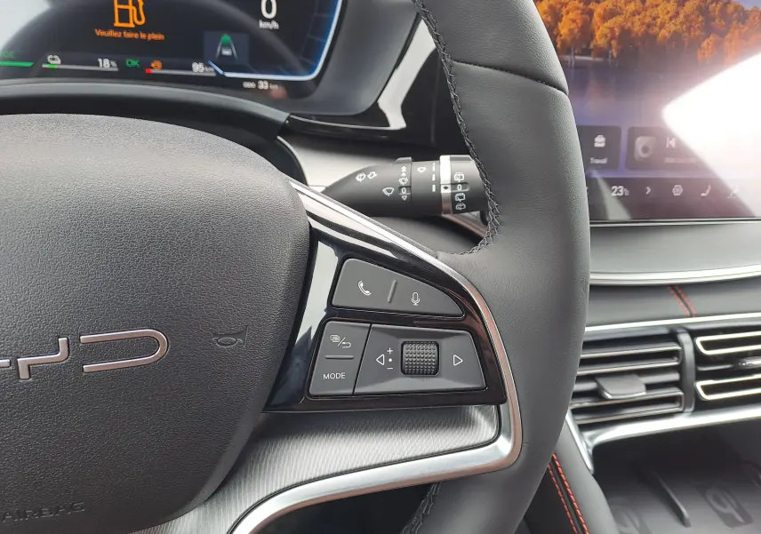 Gros plan sur le volant droit en cuir noir du BYD SEAL U 2025, avec commandes vocales et écran numérique en arrière-plan.