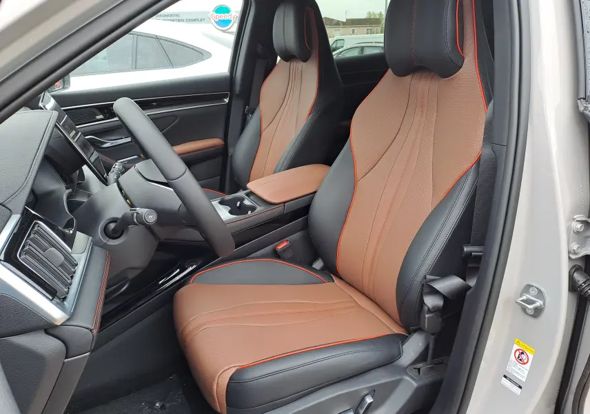 Vue intérieure côté conducteur du BYD SEAL U 2025, sièges en similicuir bicolore noir et marron avec surpiqûres orange.