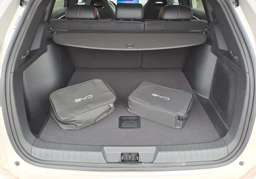 Coffre ouvert d’un BYD SEAL U 2025 blanc Boundless Cloud avec deux sacs noirs et banquette arrière rabattable.