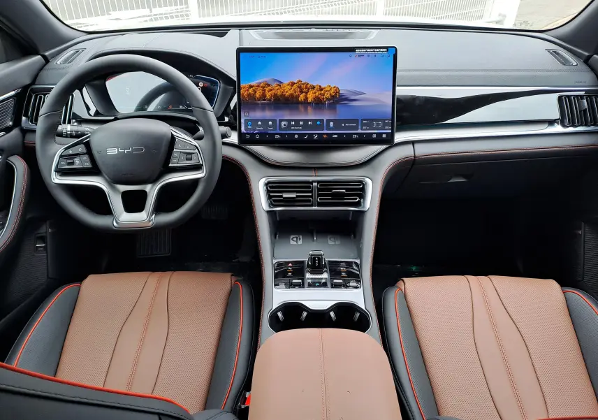 Vue intérieure avant du BYD SEAL U 2025 avec sièges en similicuir brun et noir, grand écran tactile central et volant multifonction.