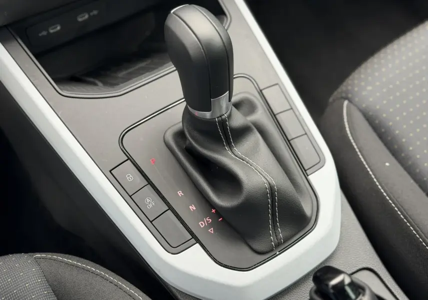 Gros plan sur la commande de boîte automatique noire et blanche du SEAT Arona TSI 115 DSG Style 2025, intérieur tissu gris.