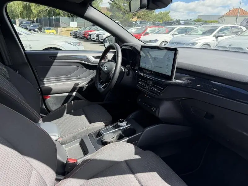 Vue intérieure côté conducteur de la Ford Focus gris lunaire avec écran tactile central et volant cuir multifonction.