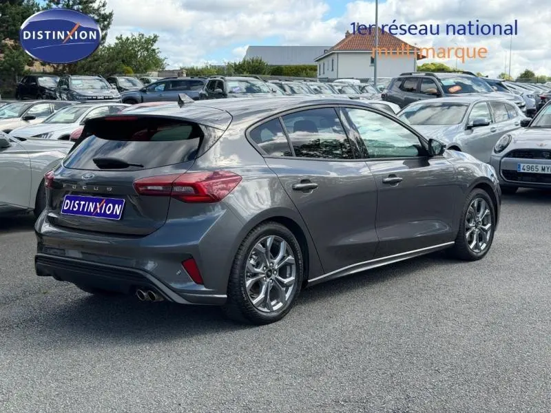 Ford Focus 2025 gris lunaire métallisé vue 3/4 arrière droit, jantes alu et feux arrière LED visibles.