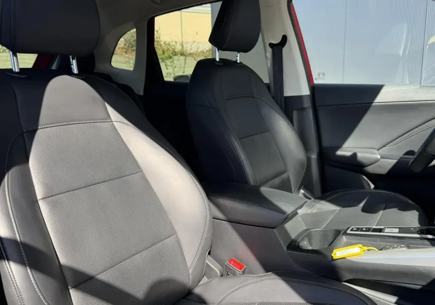 Vue intérieure côté avant droit du MG ZS 1.5 Hybrid+ 197 Luxury 2025 avec sièges tissu/similicuir noirs et accoudoir central.