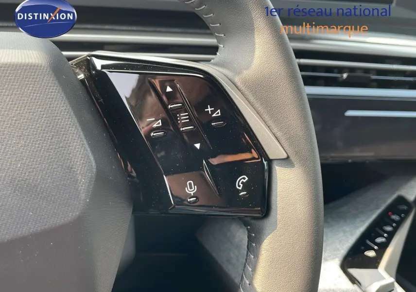 Gros plan sur les commandes au volant en cuir gris clair du Peugeot 3008 2025, version hybride essence.