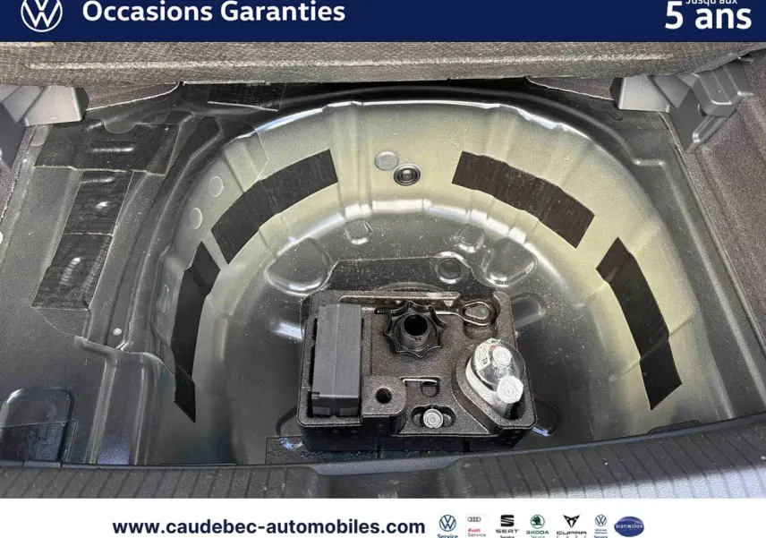 Coffre ouvert montrant la roue de secours et le kit de réparation sur une Volkswagen Polo noire intense nacrée.