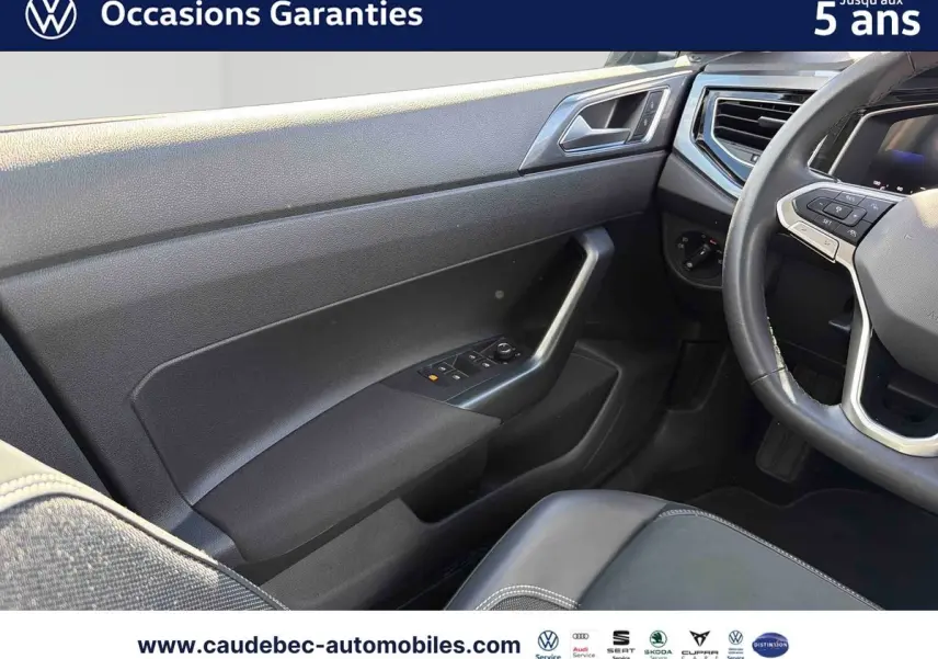 Intérieur côté conducteur de Volkswagen Polo noir intense nacré, montrant porte, volant cuir et siège partiel.