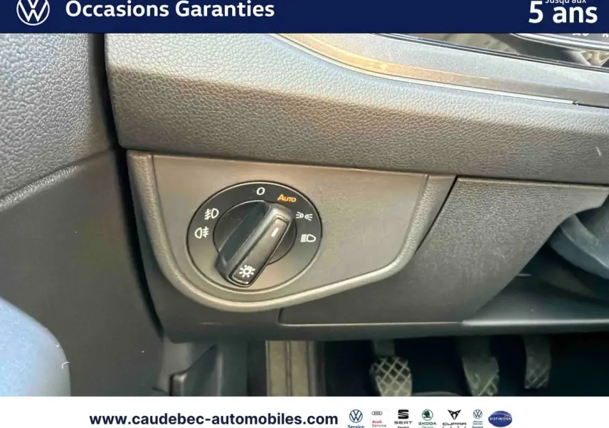 Détail du bouton de commande des phares sur le tableau de bord d’une Volkswagen Polo noire intense nacrée.