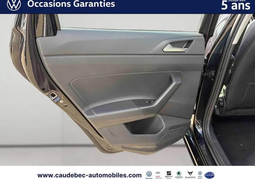 Vue rapprochée de la porte arrière gauche ouverte d’une Volkswagen Polo noire intense nacrée, montrant la garniture intérieure grise.