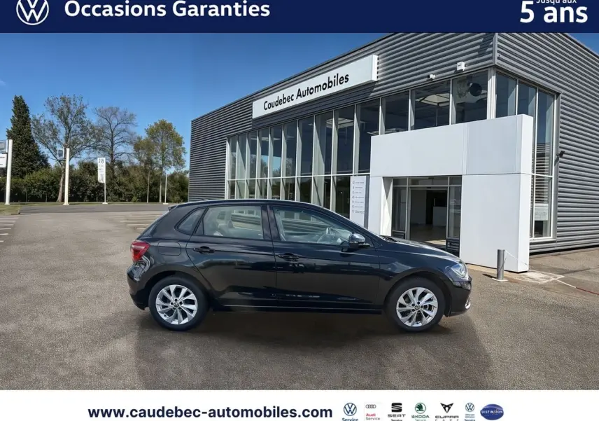 Profil gauche d'une Volkswagen Polo noire intense nacrée 2025, avec jantes alliage Palermo 16 pouces, devant un showroom.