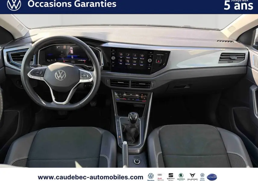 Vue intérieure avant de la Volkswagen Polo 2025, tableau de bord noir avec volant cuir multifonctions et écran tactile central.