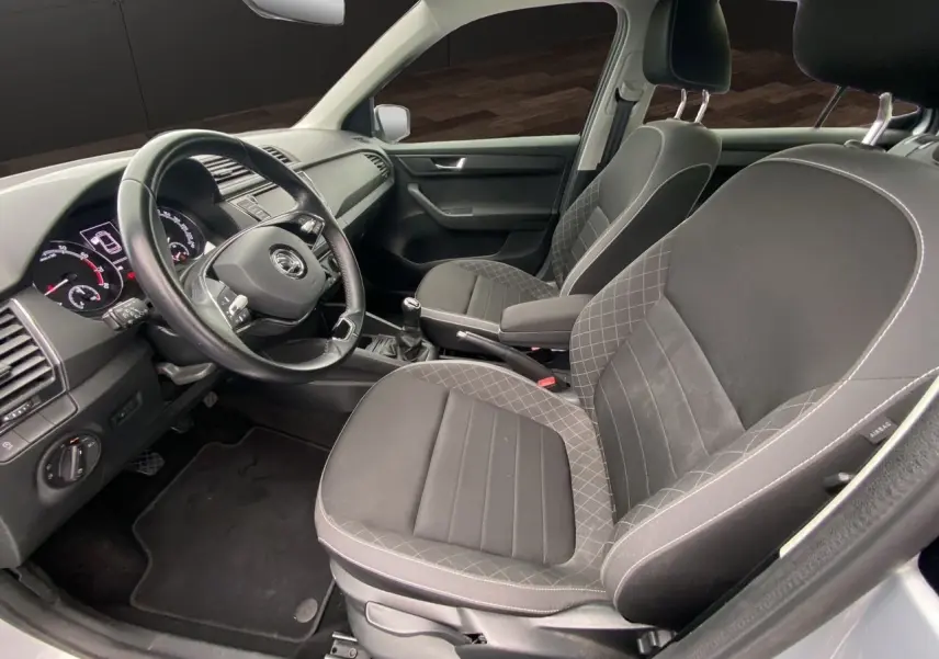 Vue intérieure côté conducteur de la Skoda Fabia gris argent 2021 avec sièges tissu noir et volant multifonction.