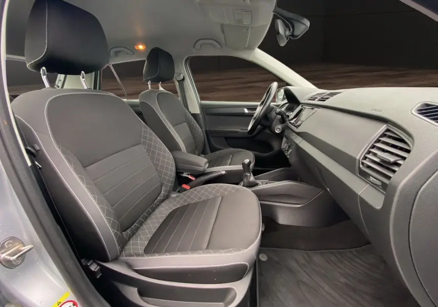 Vue intérieure côté droit de la Skoda Fabia 2021 gris argent, montrant les sièges avant et la console centrale avec boîte manuelle.