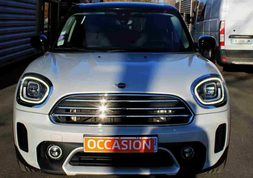Vue avant d'un MINI Countryman gris perle métal avec toit noir, calandre chromée et plaque "OCCASION" visible.