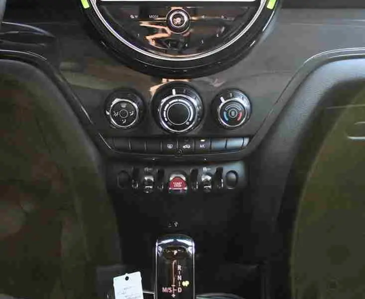 Vue centrée sur la console centrale du MINI Countryman 2020, écran tactile rond avec éclairage vert pâle et levier de vitesse automatique.