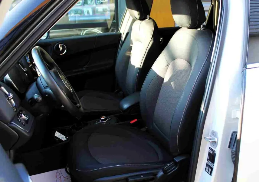 Vue intérieure côté conducteur du MINI Countryman gris perle avec sièges tissu noirs et volant cuir.