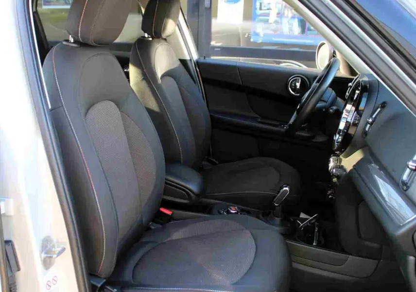 Vue intérieure côté conducteur du MINI Countryman gris perle métal, sièges tissu noir avec surpiqûres contrastées.