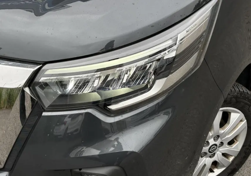 Gros plan sur le phare avant droit et la jante alliage 17'' du Nissan Primastar gris Comète, version 2025.