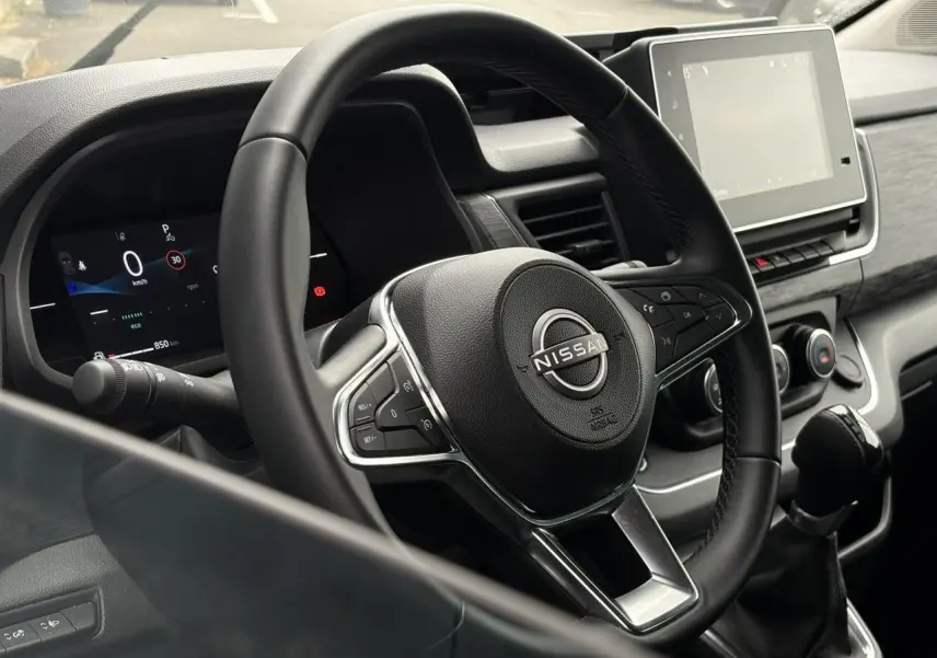 Vue rapprochée du volant et du tableau de bord numérique du Nissan Primastar 2025, intérieur noir moderne.
