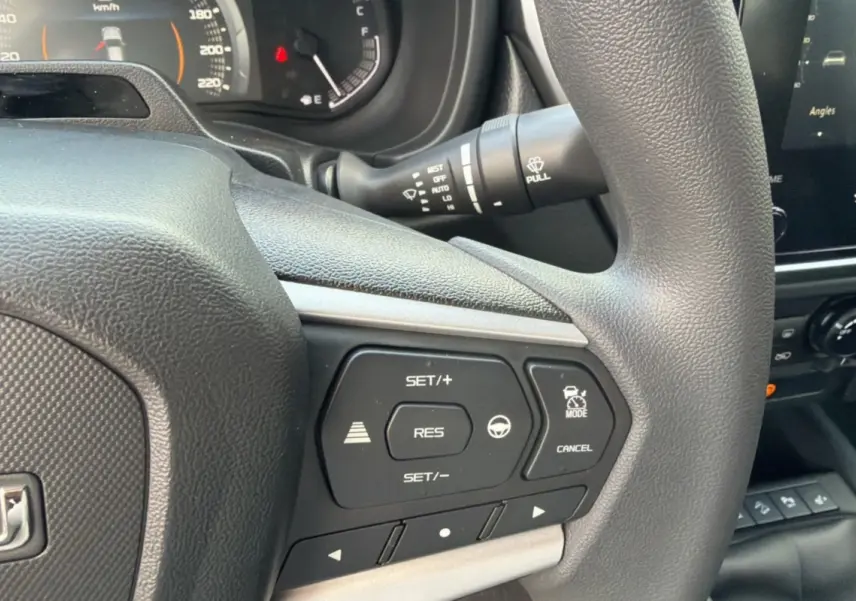 Gros plan sur le volant multifonctions de l'Isuzu D-MAX 2026, avec commandes de régulateur et tableau de bord partiel.