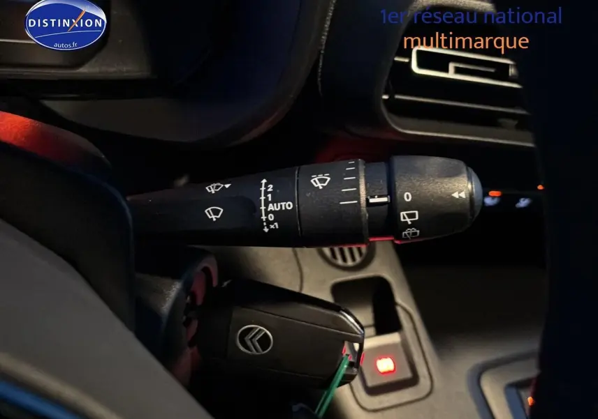 Gros plan intérieur sur la commande d’essuie-glace et la clé noire avec logo Citroën du Berlingo Fourgon blanc.