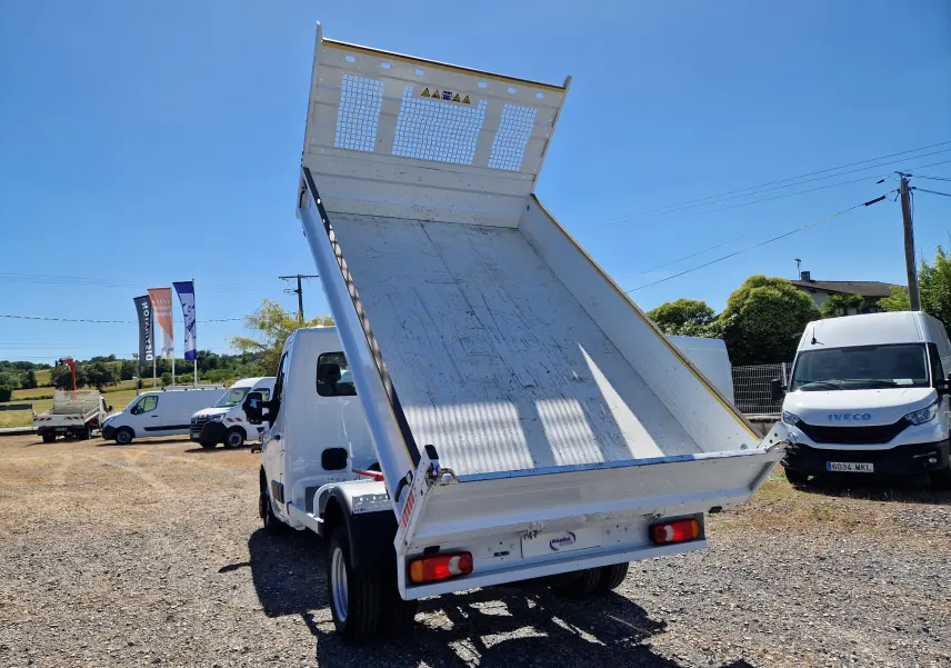 Vue arrière en léger angle d’un Renault Master Châssis Cabine blanc avec benne basculante relevée sur un terrain extérieur.