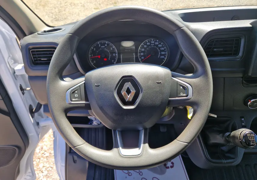Vue intérieure centrée sur le volant noir du Renault Master Benne blanc, avec levier de vitesse manuel visible à droite.