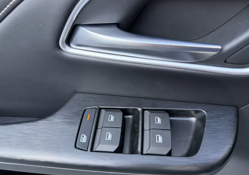 Gros plan sur la commande des vitres côté conducteur du MG ZS 1.5 L Hybrid+ 2026, finition noire intérieure.