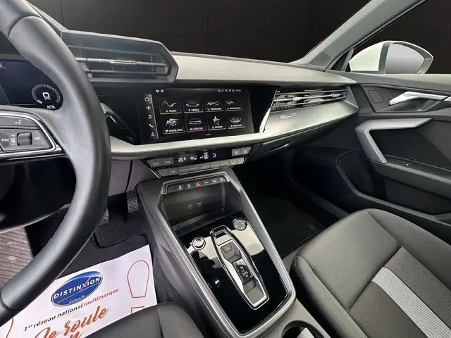 Vue intérieure de l'Audi A3 Sportback 2024, tableau de bord et console centrale noirs avec écran digital large.