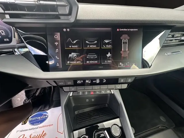 Vue rapprochée de l'écran tactile central et de la console de l'Audi A3 Sportback blanche Arkona 2024 avec interface Apple CarPlay.