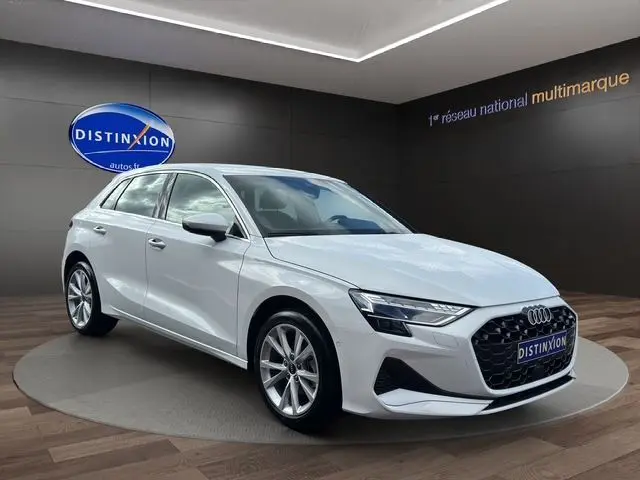 Audi A3 Sportback blanc Arkona vue 3/4 avant dans un showroom avec calandre noire et jantes alliage.