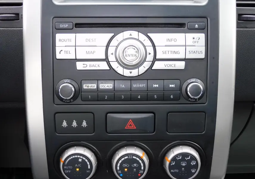 Gros plan sur la console centrale du Nissan X-TRAIL noir 2011, mettant en valeur les commandes audio et climatisation.