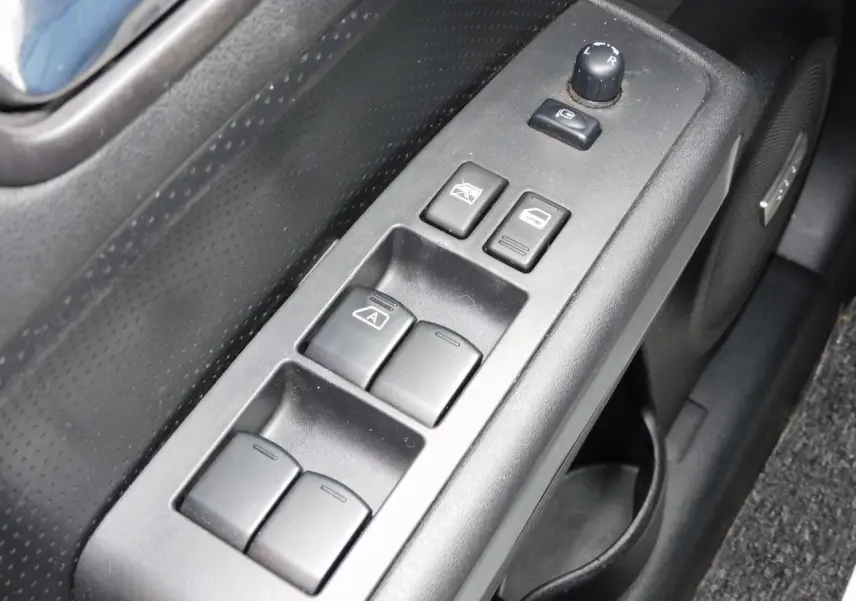 Gros plan sur la commande des vitres côté conducteur du Nissan X-TRAIL noir, avec haut-parleur Bose intégré visible.